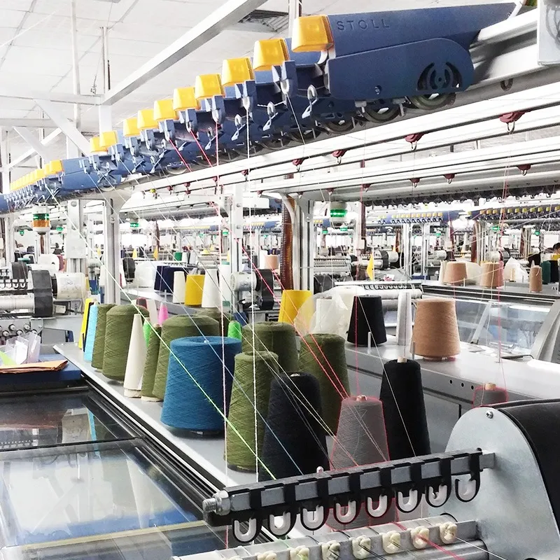 Computergesteuerte Strickmaschinen mit bunten Garnkonen in einem HKS-Werk